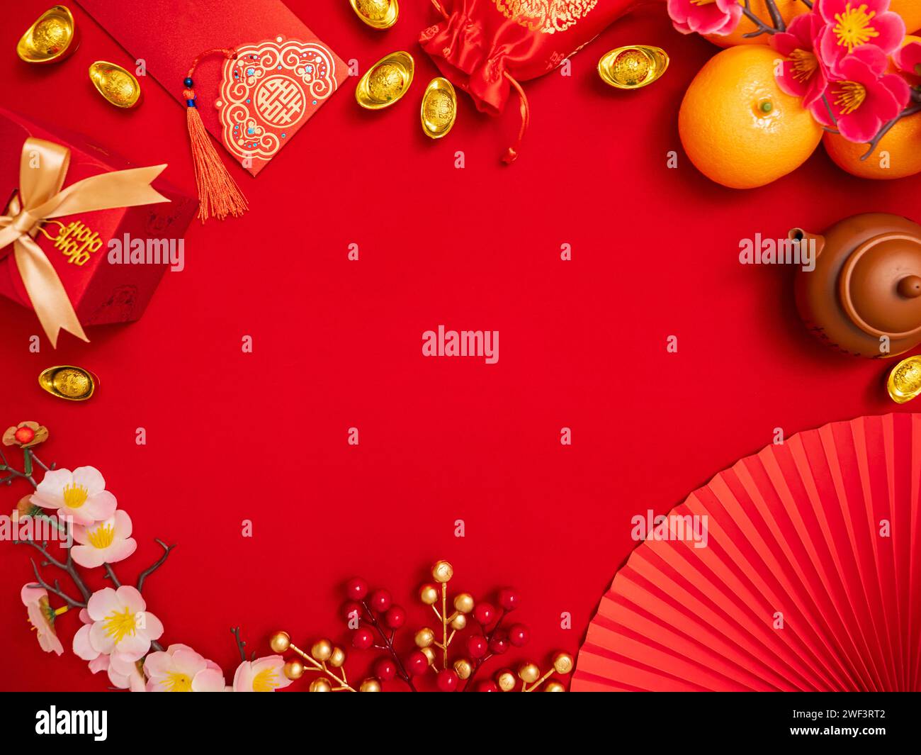 Flache Lage des Glücksgegenstandes Dekoration Ornament für chinesische Mondneujahrfeier roter Hintergrund mit alten chinesischen Goldbarren, Geschenkbox, Papierventilator Stockfoto