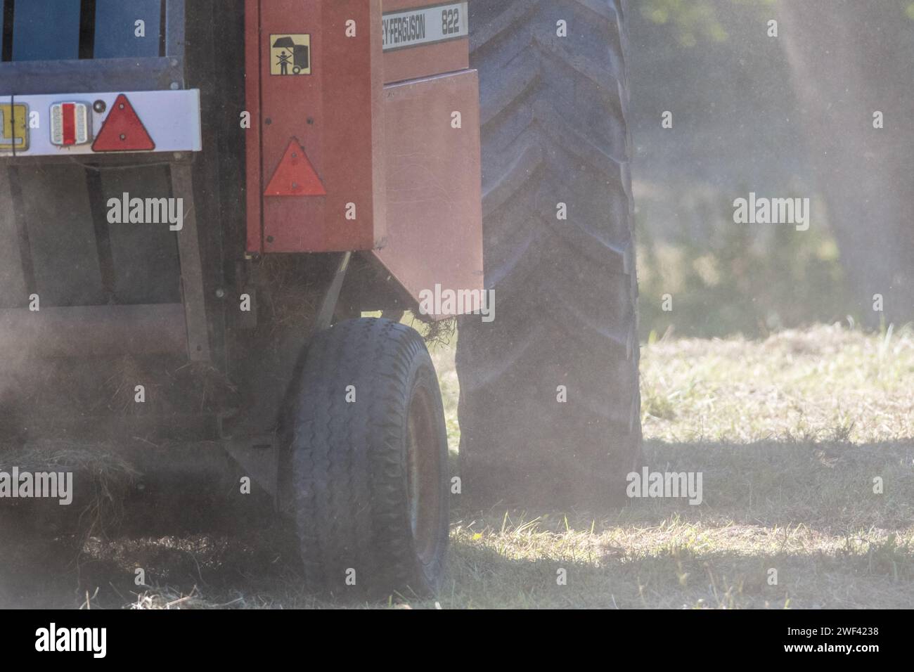 Mähen der Wildblumenwiesen im Herbst in Hawthorn Hive, County Durham. Eine Nahaufnahme der Räder eines Traktors und eines Ballers, der Staub aufwirbelt Stockfoto