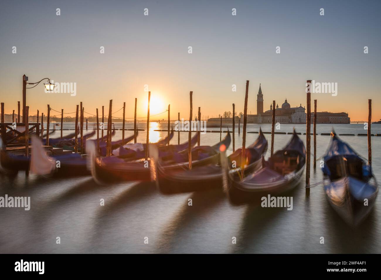 Lange Exposition von Venedig, Italien mit verankerten Gondeln auf dem Canal Grande bei Sonnenaufgang. Stockfoto