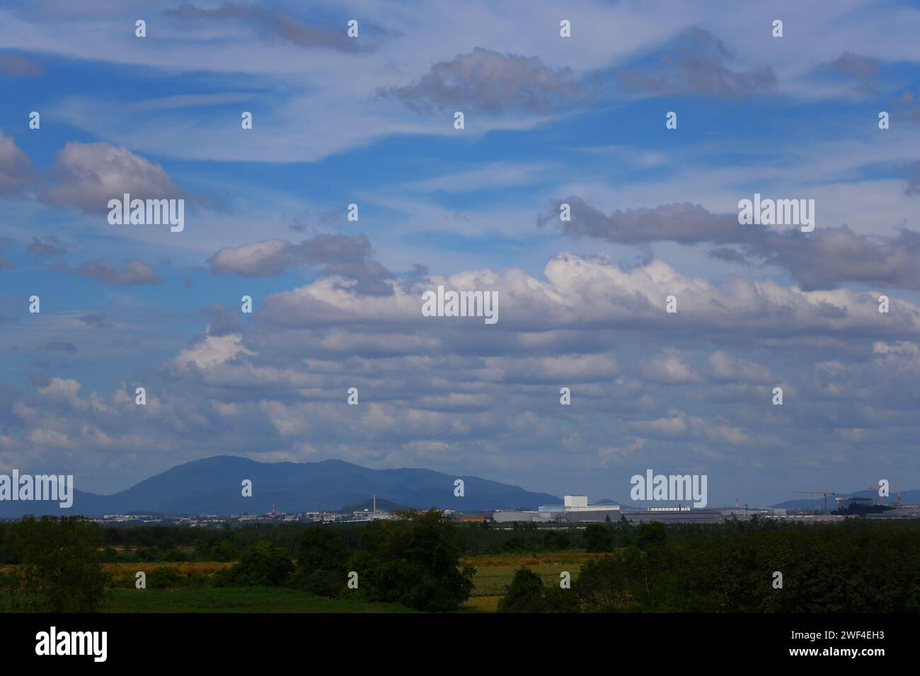 Blick auf die Wiese und die Stadt vor der Kulisse der Berge und des blauen Himmels am Tag. Stockfoto