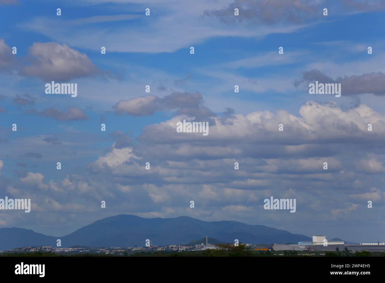 Blick auf die Wiese und die Stadt vor der Kulisse der Berge und des blauen Himmels am Tag. Stockfoto