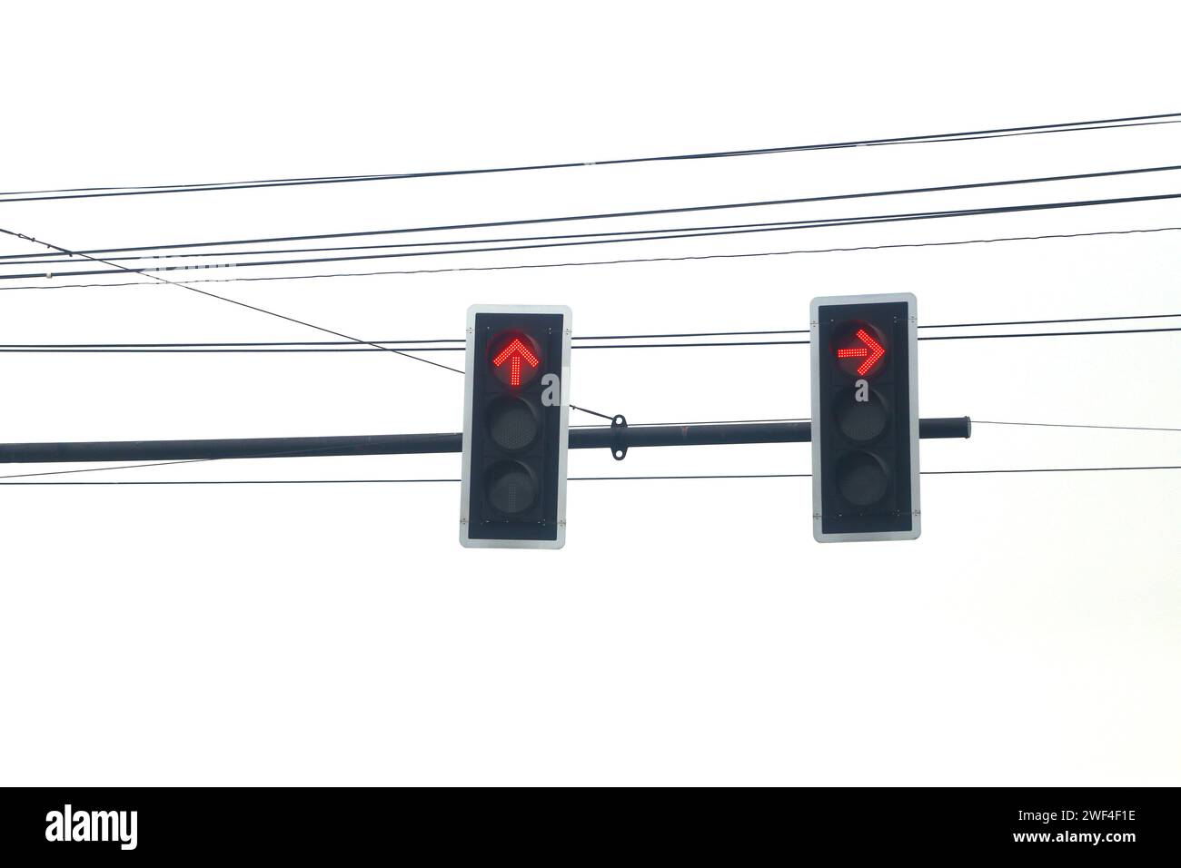Rote Ampeln, die Ihnen sagen, dass Sie isoliert auf weißem Hintergrund anhalten sollen und hinter dem schwarzen Draht steht. Stockfoto