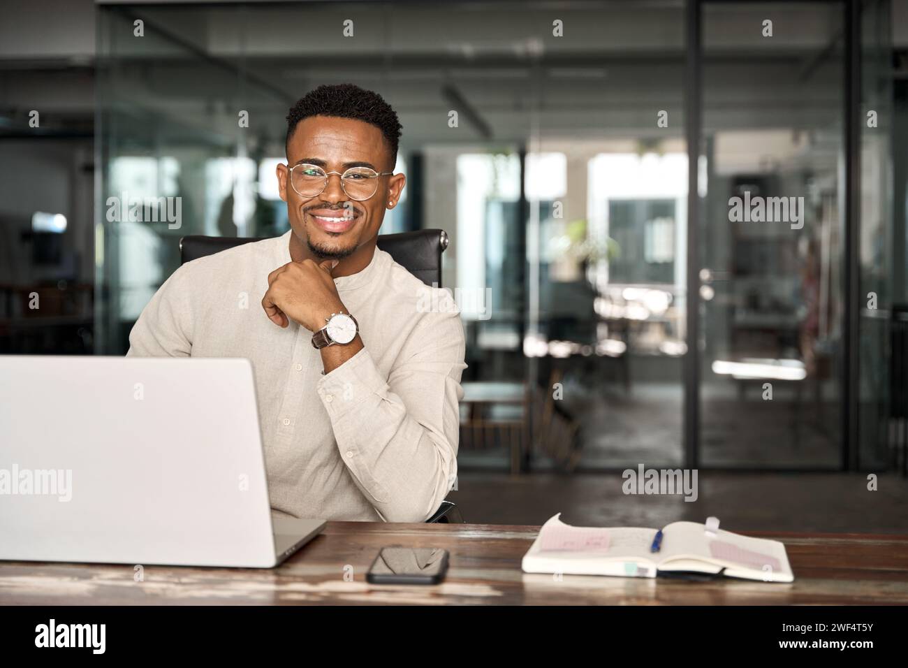 Glücklicher professioneller afrikanischer Geschäftsmann, der bei der Arbeit auf die Kamera schaut, Porträt. Stockfoto