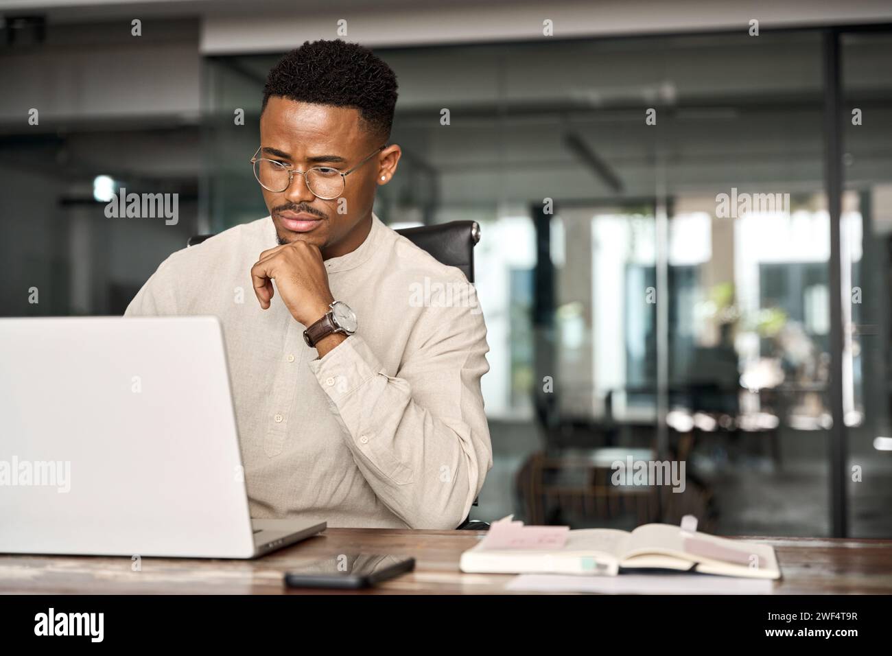 Ein beschäftigter afrikanischer Geschäftsmann denkt an Online-Investitionen und arbeitet an Laptops. Stockfoto
