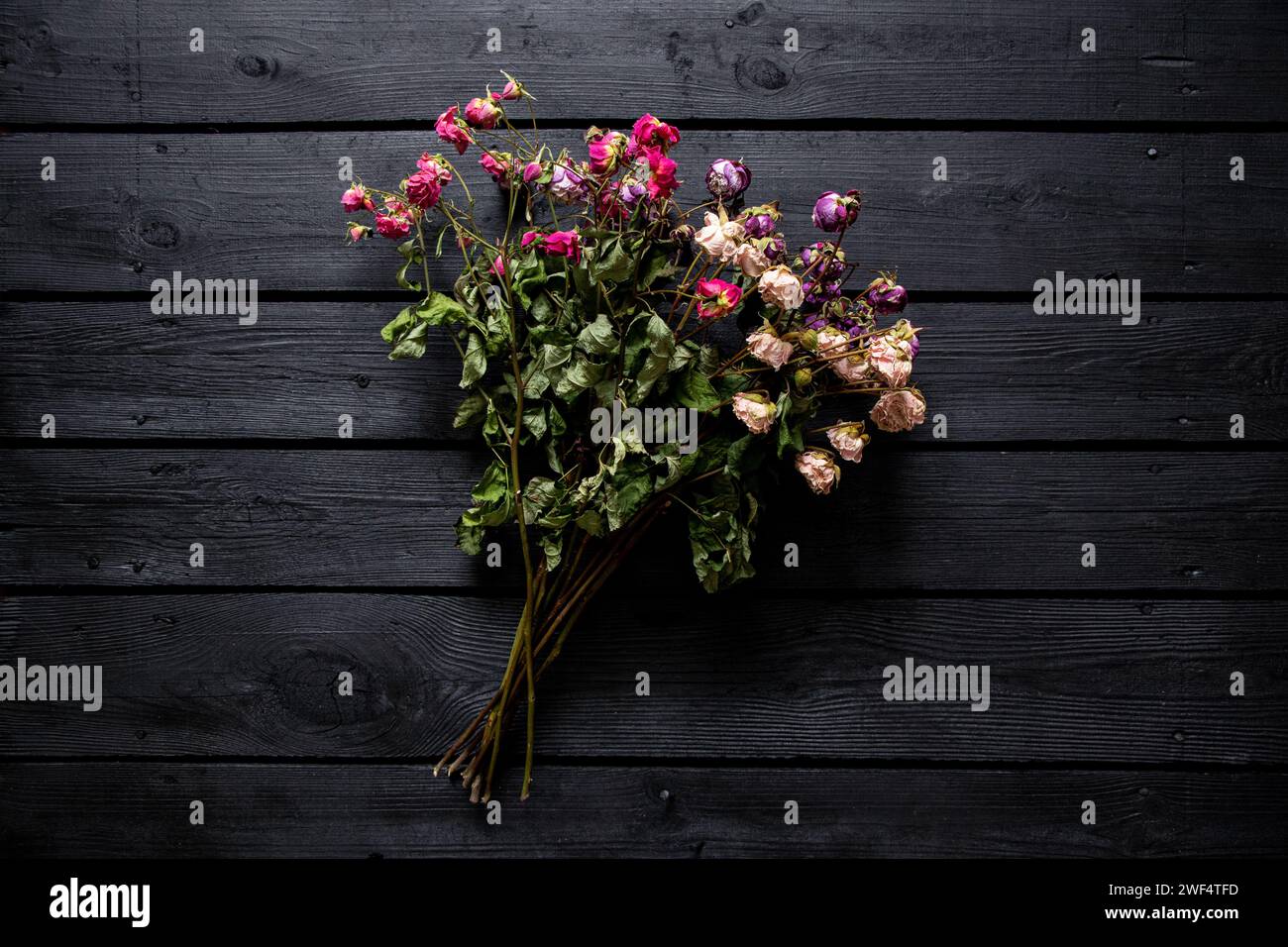 Ein Strauß getrockneter Rosen auf einem schwarzen Holzbrett, ein Strauß getrockneter Blumen auf dem Tisch Stockfoto