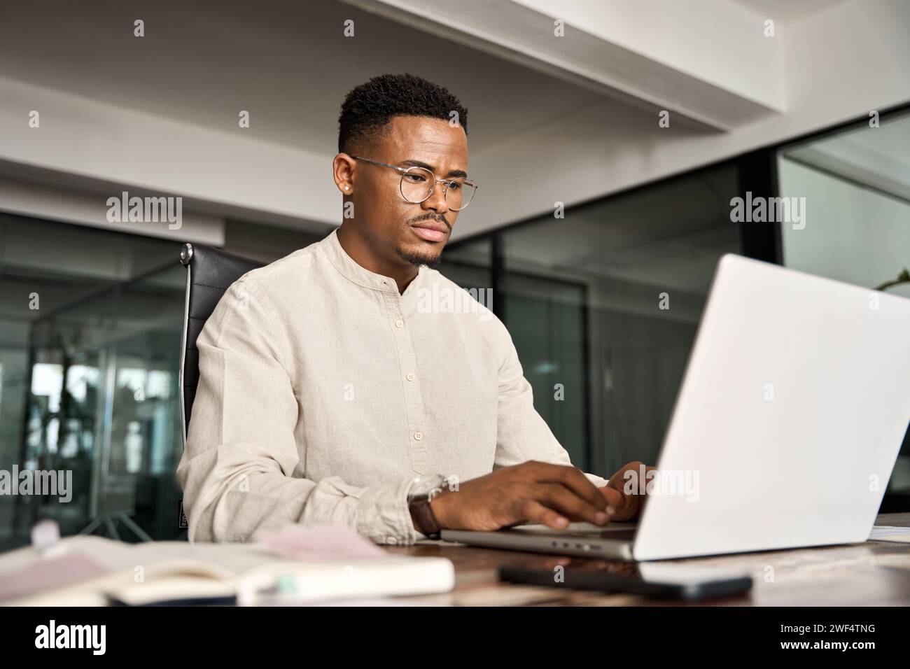 Beschäftigter professioneller afrikanischer Geschäftsmann, der im Büro mit einem Laptop arbeitet. Stockfoto