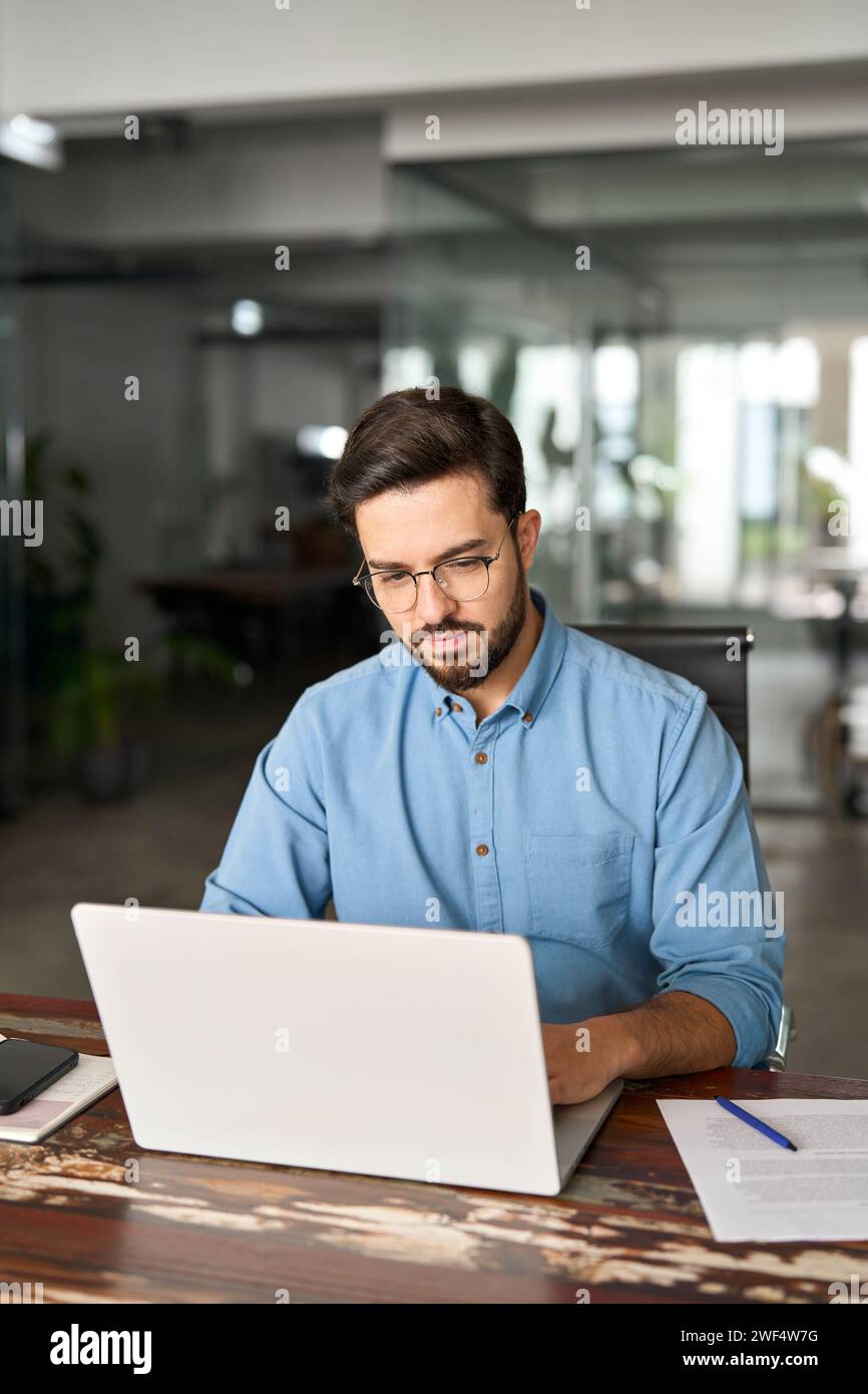 Geschäftiger Geschäftsmann mit Laptop, der im Büro arbeitet, vertikal. Stockfoto