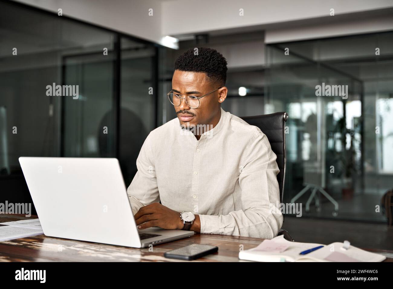 Beschäftigter männlicher afrikanischer Firmenangestellter, der im Büro mit einem Laptop arbeitet. Stockfoto