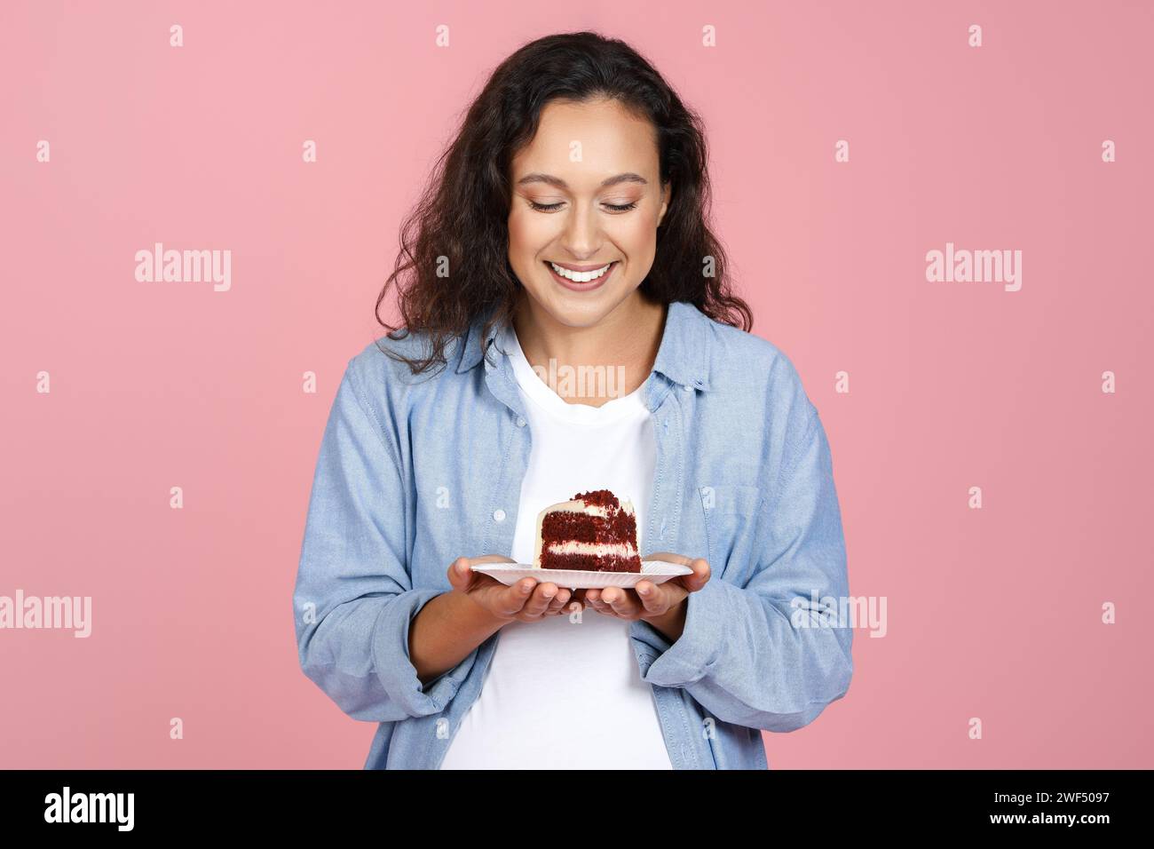 Glückliche junge schwangere Frau, die leckeren Kuchen hält Stockfoto