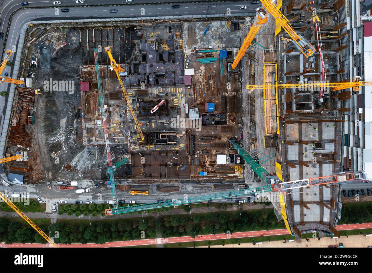 Von oben nach unten auf die Baustelle mit Turmkränen, die arbeiten und ein neues Appartementhaus in einem Wolkenkratzer bauen. Bauindustrie Stockfoto