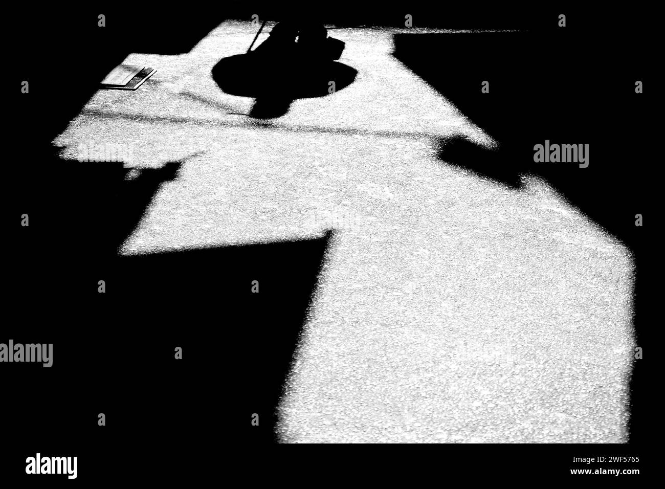 Schatten-Silhouette eines nicht erkennbaren Mannes, der mit Stock in der Gasse geht, in Schwarz-weiß Stockfoto