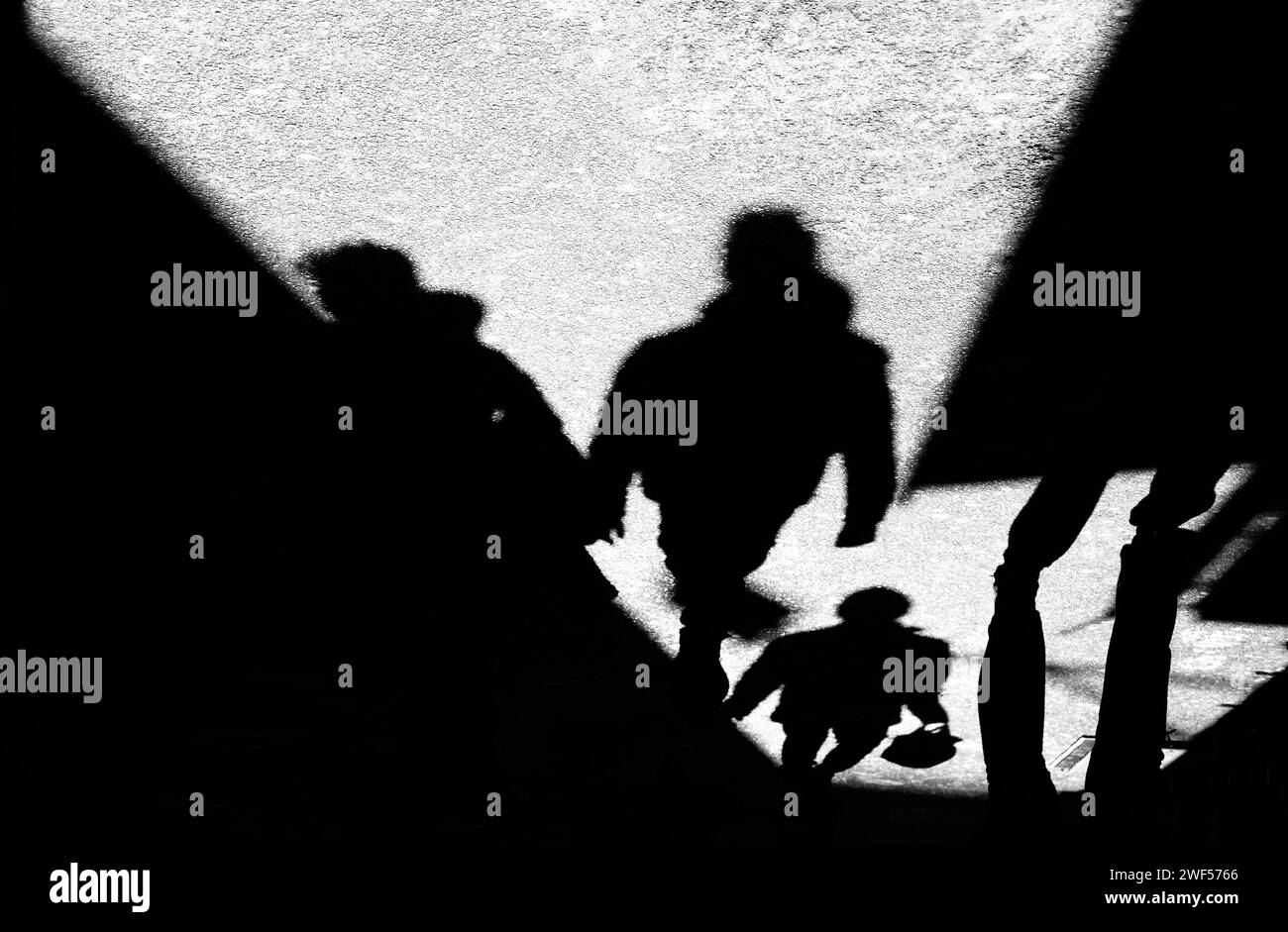 Schatten-Silhouette von nicht erkennbaren Menschen, die in einer Gasse laufen, in Schwarz-weiß Stockfoto