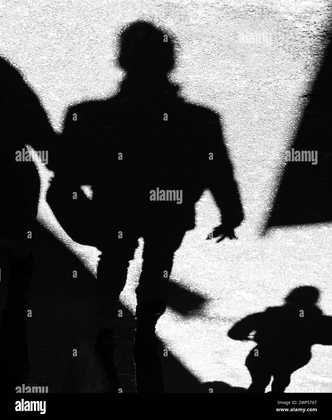 Schatten-Silhouette von nicht erkennbaren Menschen, die auf der Stadtstraße laufen, in Schwarz-weiß Stockfoto