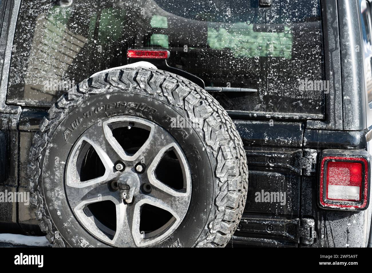 Das Heck eines schwarzen Jeep Wrangler bedeckt mit Winterstaub und Streusalz Stockfoto