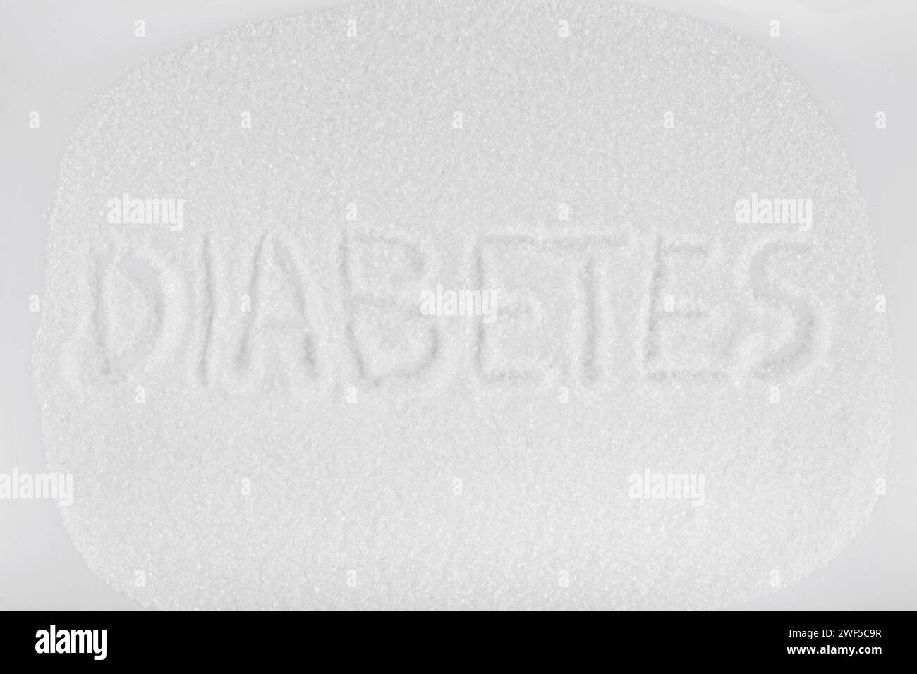 Weißer Kristallzucker und Phrase Diabetes auf weißem Hintergrund Stockfoto
