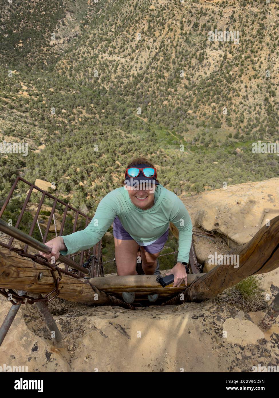 Frau klettert auf Leiter auf Balcony House Tour in Mesa Verde Stockfoto