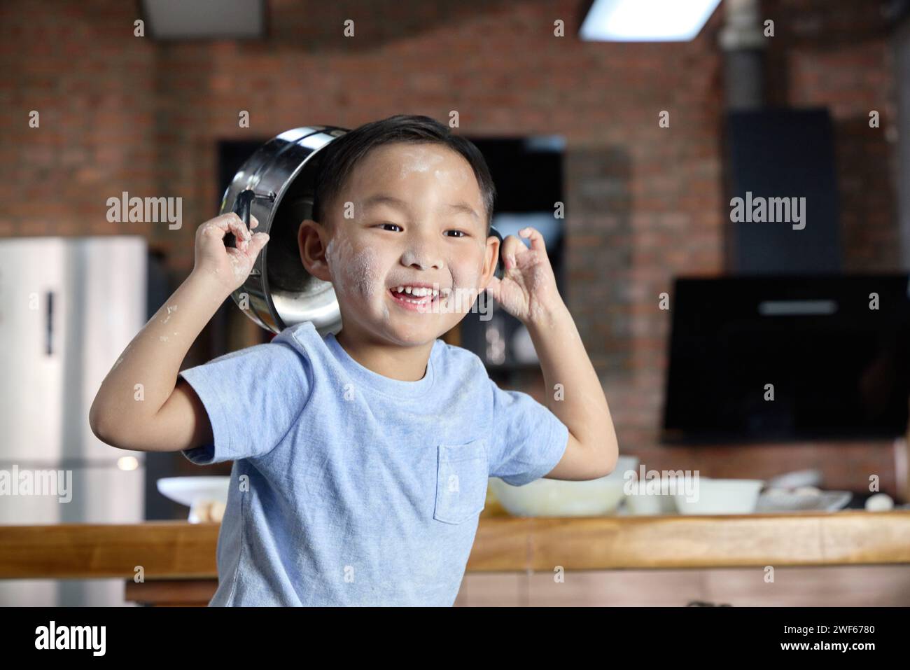Ein glücklicher kleiner Junge, der mit einem Topf auf dem Kopf spielt Stockfoto
