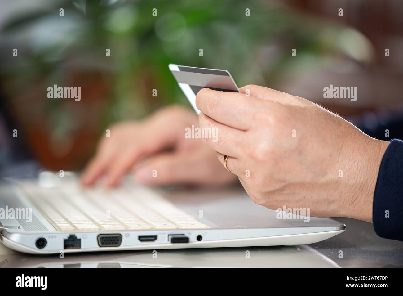 Die Hände eines Mannes mittleren Alters geben Kreditkarteninformationen ein Stockfoto