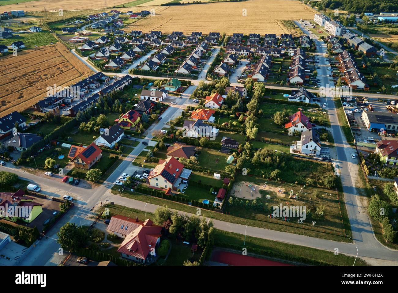 Wohnhäuser in einer kleinen Stadt in der Nähe von landwirtschaftlichen Feldern, Vogelperspektive. Luftaufnahme des europäischen Vorstadtviertels mit Stadthäusern. Immobilien in Stockfoto