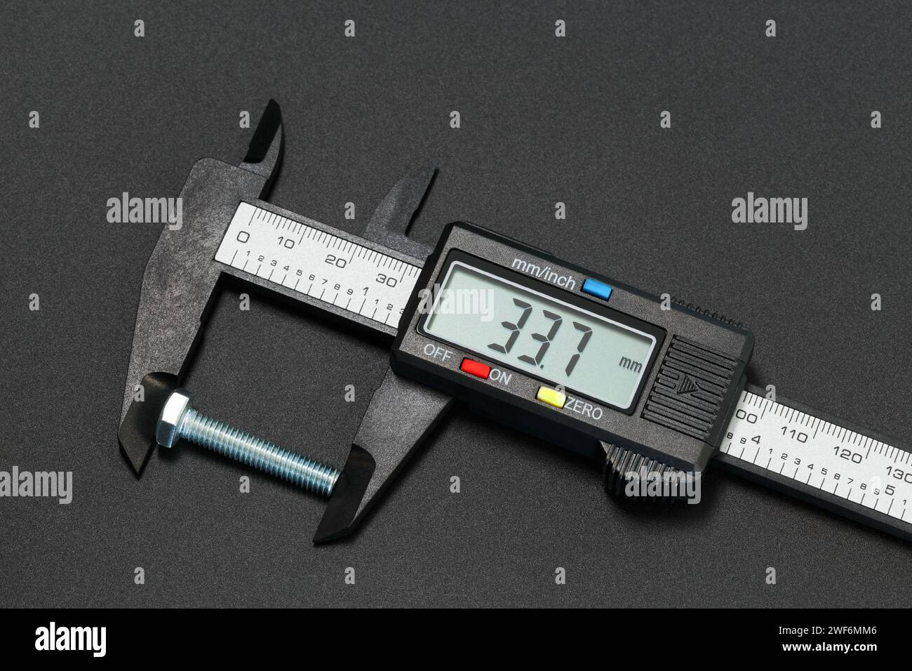 Messung der Schraubenlänge mit einem digitalen Messschieber. Makrofotografie auf dunklem Hintergrund Stockfoto
