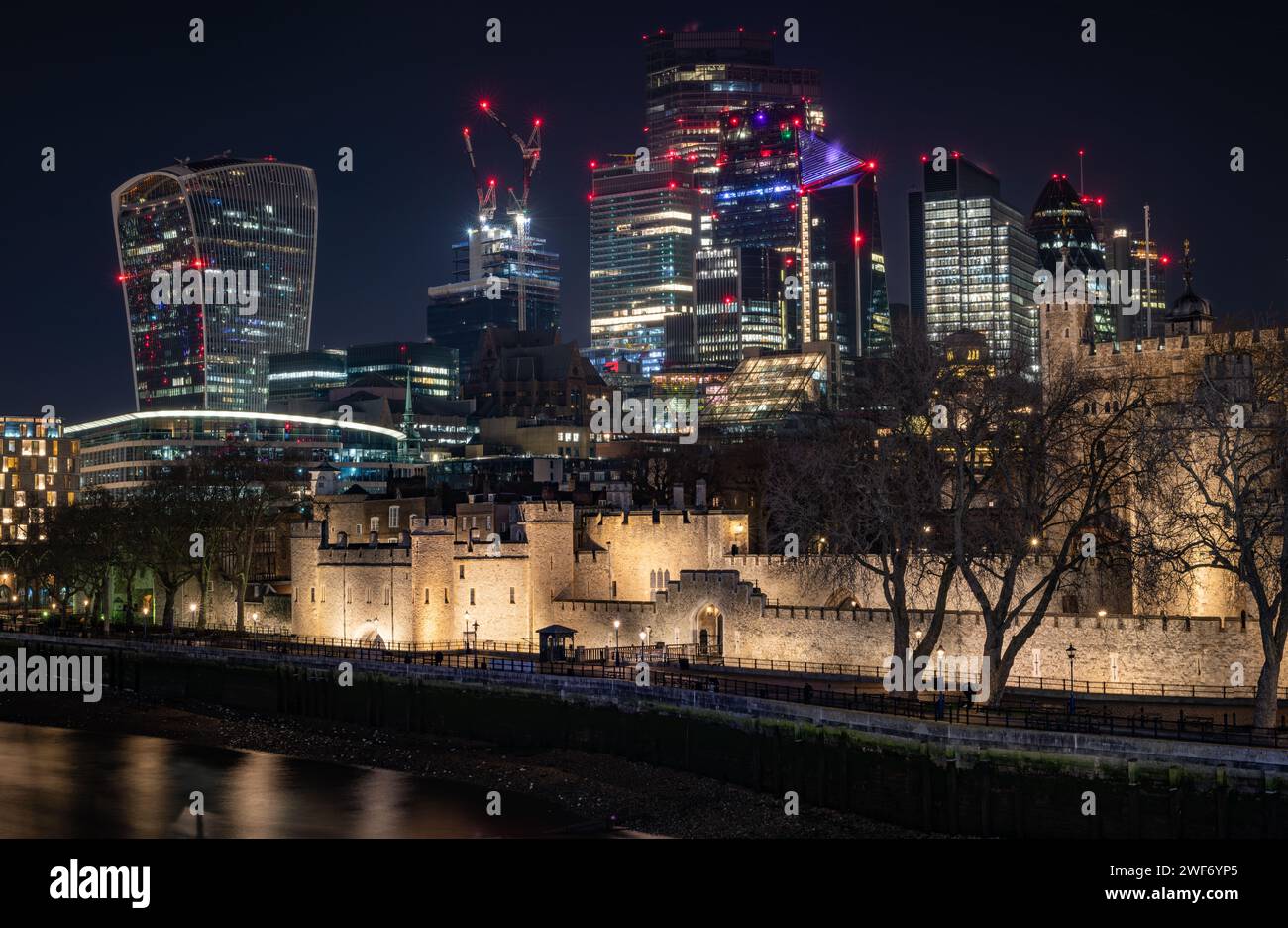 London. UK-01.27.2024. Der Tower of London bei Nacht mit Wolkenkratzern in der City of London im Hintergrund. Nachtsicht Langzeitbelichtung. Stockfoto