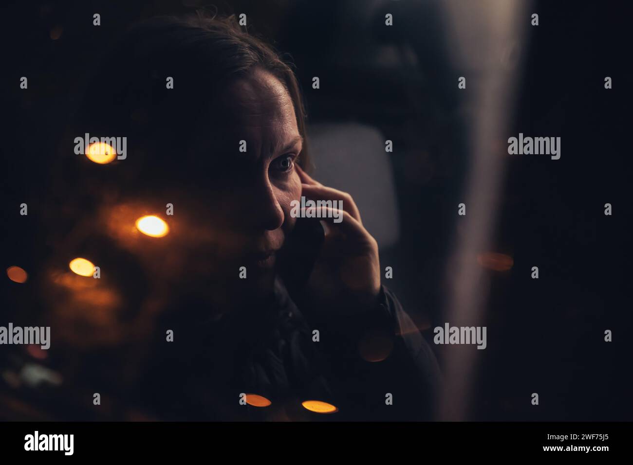 Frau, die nachts vom Rücksitz des Autos aus auf dem Handy spricht, durch das Fenster von außen gesehen, selektiver Fokus Stockfoto