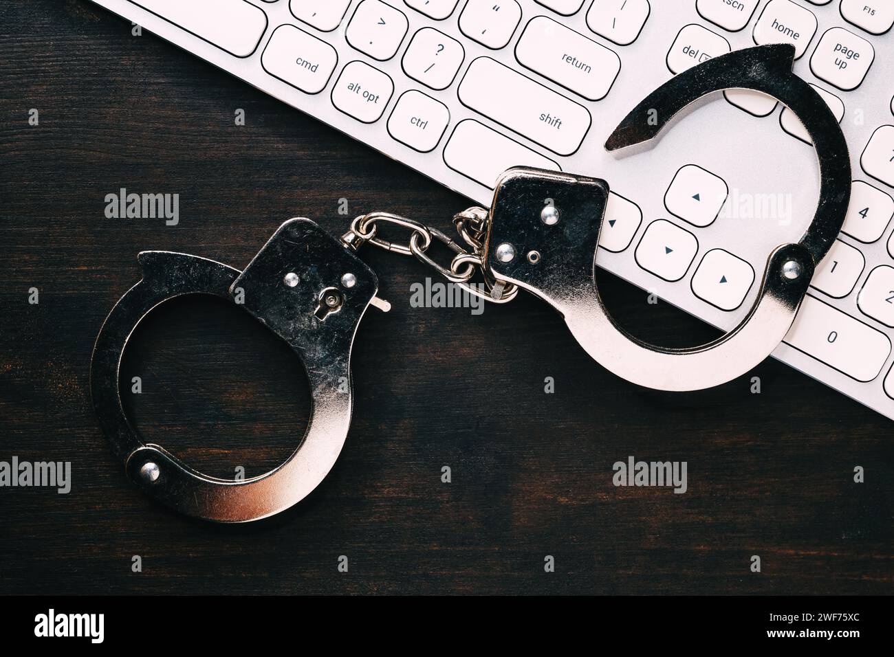 High-Tech-IT-Konzept zur Verhaftung von Cyberkriminalität, Bild von Polizeihandschellen über Computertastatur, selektiver Fokus Stockfoto