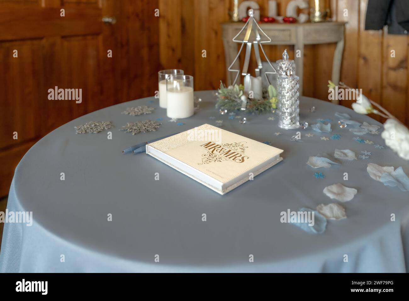 Ein Rezeptionstisch zieht die Aufmerksamkeit auf sich, mit seinem „Mr & Mrs“-Gästebuch, umgeben von sanftem Kerzenlicht und dekorativen Akzenten, die für Gäste bereit sind Stockfoto