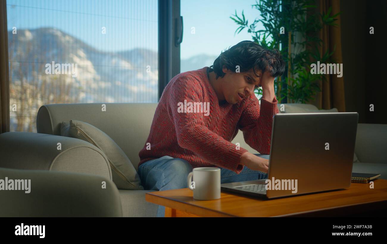 Männliche sitzen auf dem Sofa, leiden Schmerzen in der Brust, haben Herzinfarkt, halten die Brust massieren, während sie mit dem Laptop arbeiten. Männlicher Atembeschwerden Schlaganfall zu Hause. Stockfoto