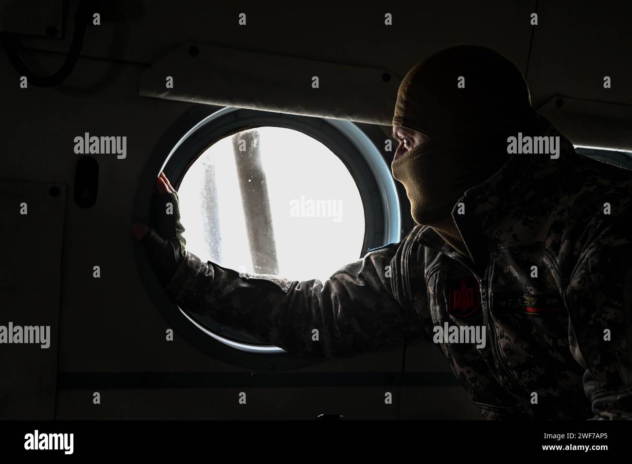 UKRAINE - 24. JANUAR 2024 - Ein Soldat der 11. Separaten Armee-Luftfahrt-Brigade 'Cherson' der Streitkräfte der Ukraine schaut durch das Hubschrauberfenster, Ukraine. Stockfoto