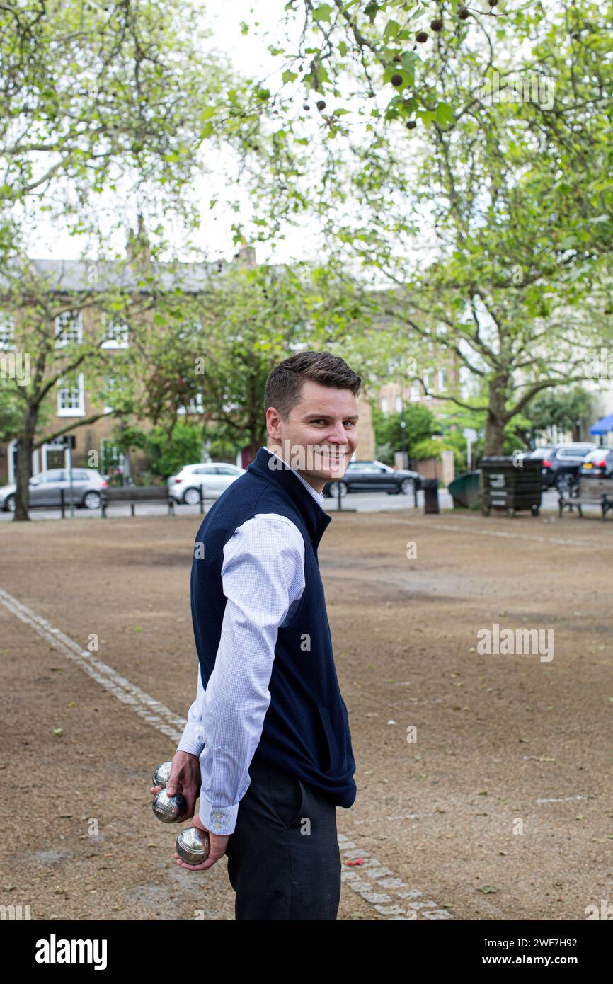 Junge Männer spielen Boules in einem kleinen offenen Raum in London, England Stockfoto