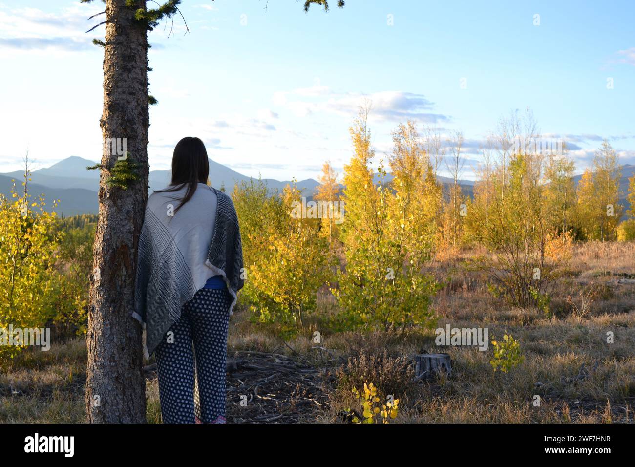Frauen stehen friedlich und blicken durch Herbstbäume auf den Mountain Peak Stockfoto