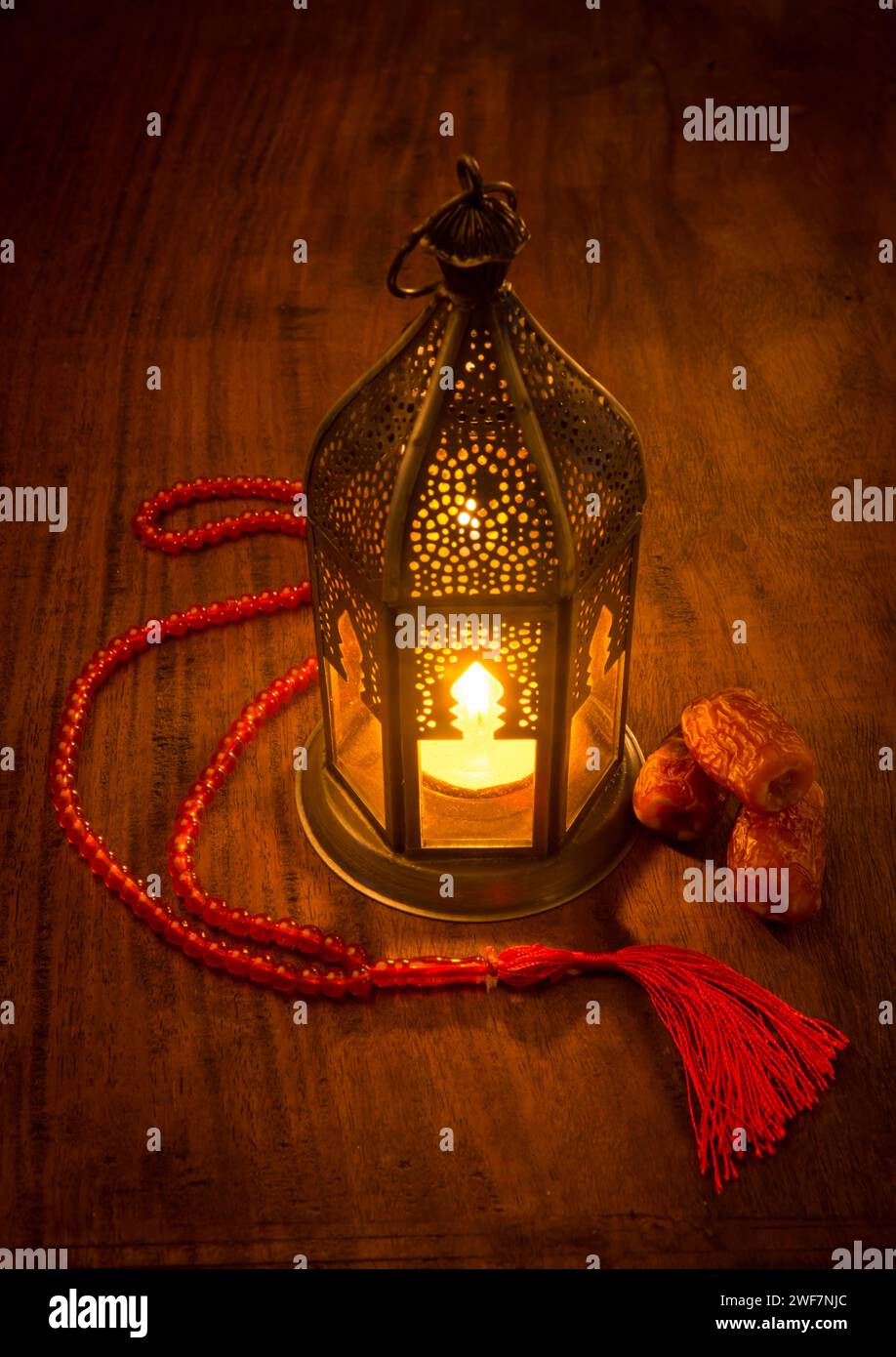 Eine wunderschöne beleuchtete Ramadan-Lampe mit wenigen Datteln und islamischem Rosenkranz. Traditionelle Ramadan-Lampe. Stockfoto