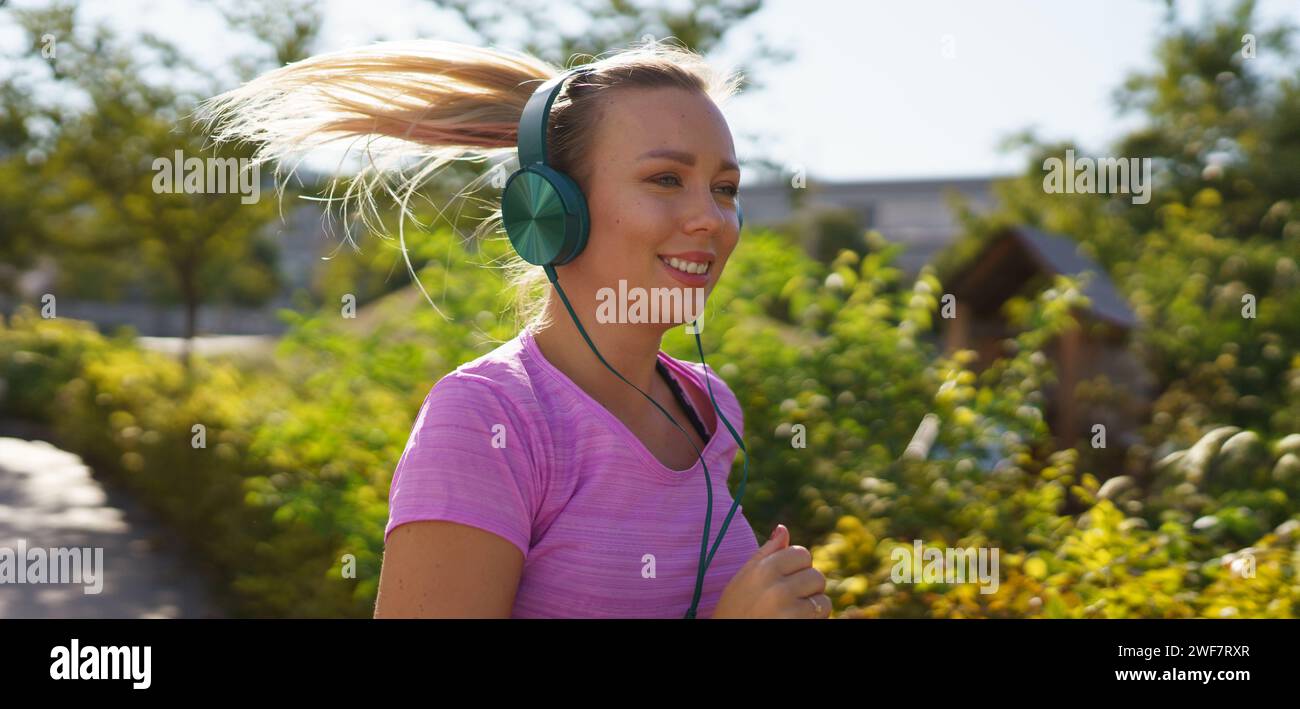 Eine junge Frau, die draußen läuft und Musik hört. Sport nach der Arbeit für eine gute psychische Gesundheit, körperliche Gesundheit, Stressabbau und Stimmung Stockfoto