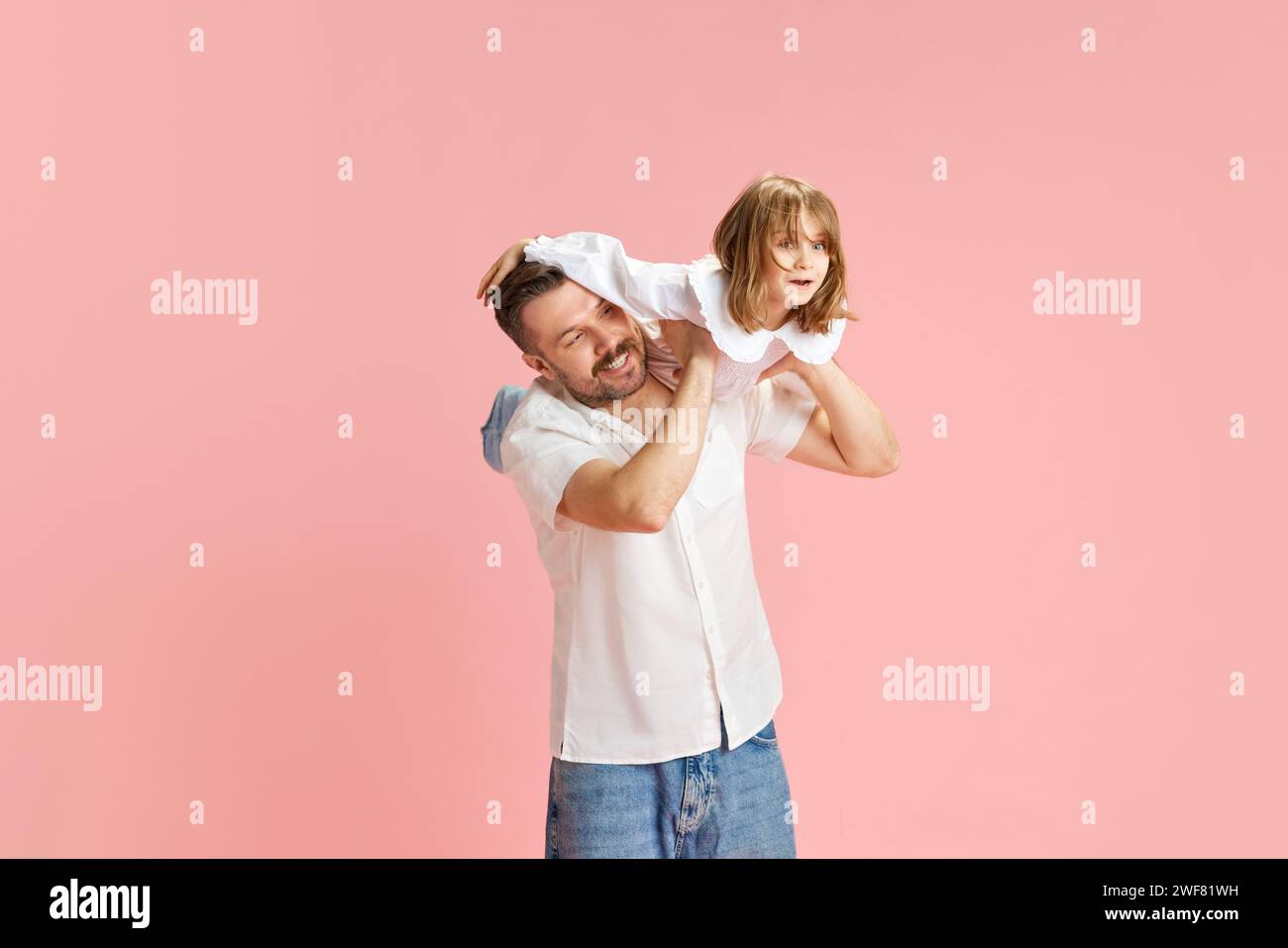 Fröhlicher Vater und Kind, das fantasievolle Spiele spielen, simulieren das Fliegen vor pinkfarbenem Hintergrund. Das Konzept des Internationalen Tages des Glücks Stockfoto