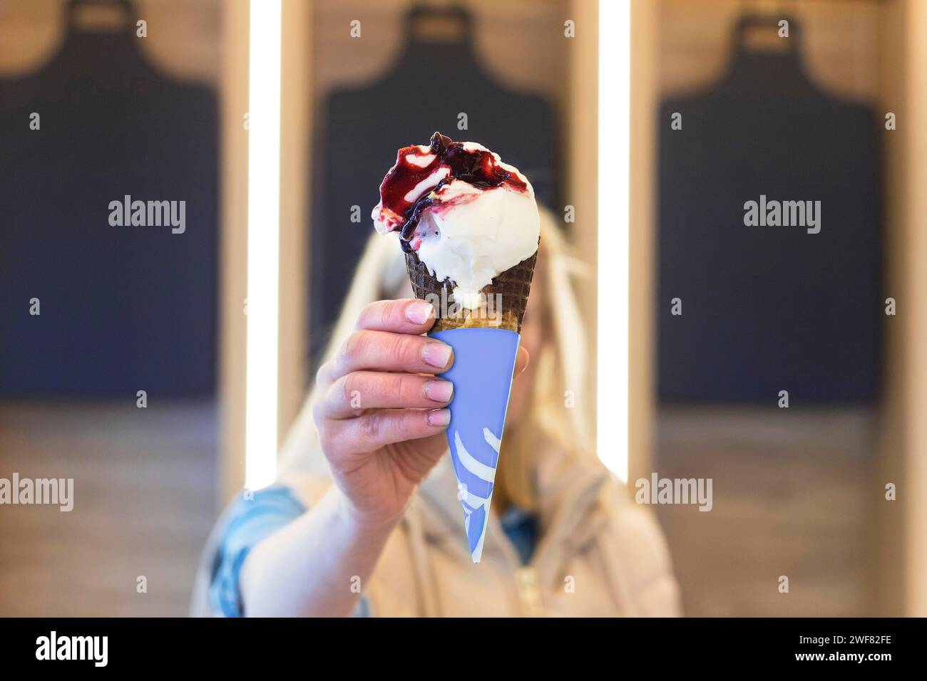 Die Frau hält Eisbecher vor ihr Gesicht, weicher Fokus Stockfoto
