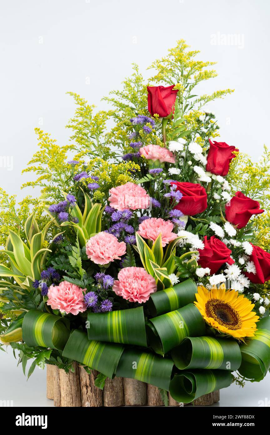 Buntes Blumenstrauß in Holzkiste isoliert auf weißem Studiohintergrund Stockfoto