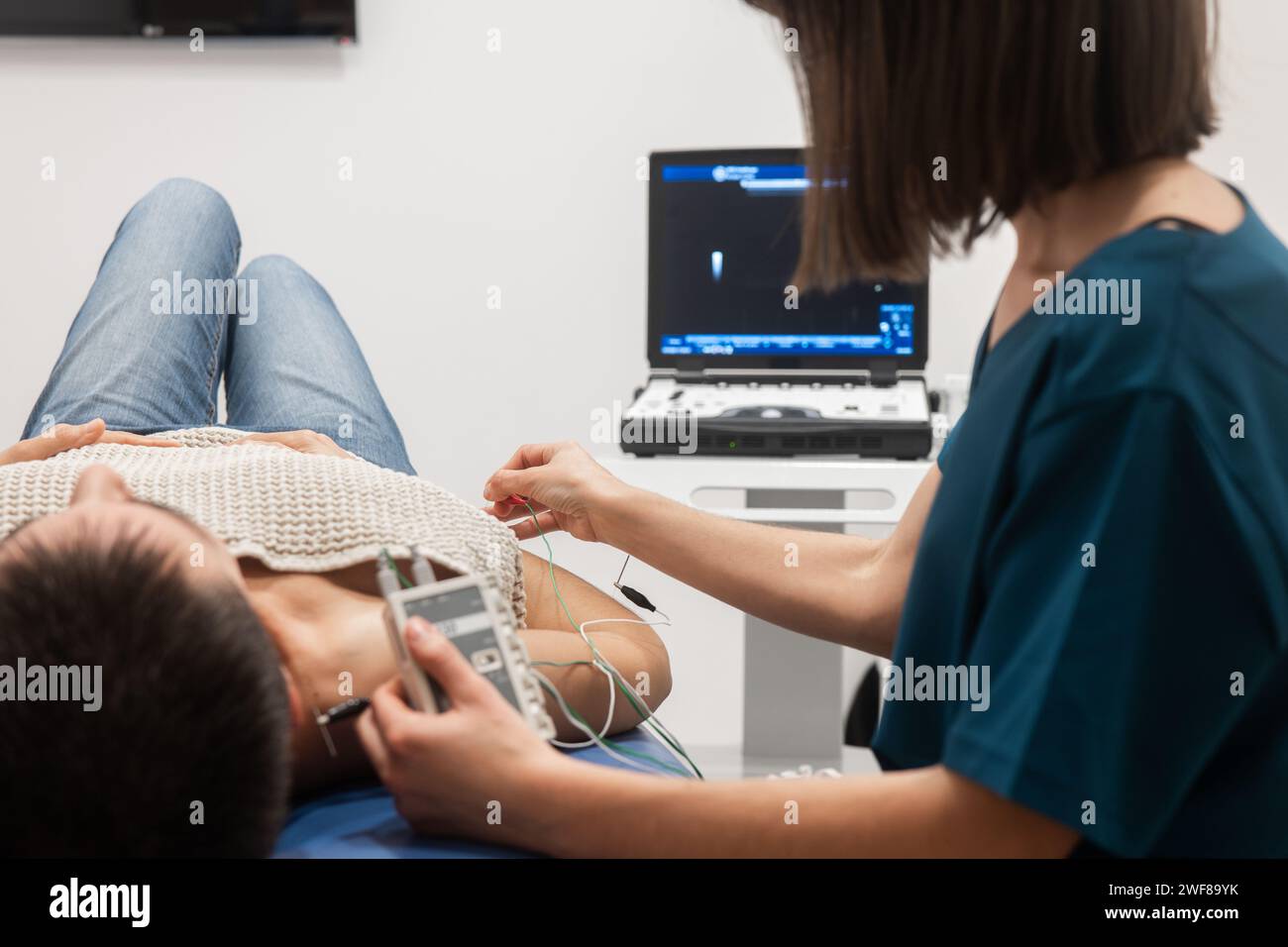 Ein männlicher Patient legt sich hin und erhält ein Echokardiogramm, das von einem medizinischen Fachpersonal durchgeführt wurde Stockfoto