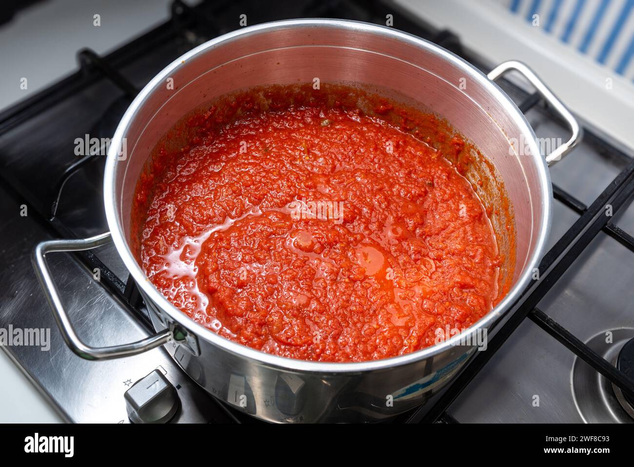 Roter Tomatensoße nach neapolitanischer Art wird in einem Topf auf einem Kochfeld gekocht, Blick von oben. Tomaten-Ragout-Fleisch in einem Stahltopf Stockfoto