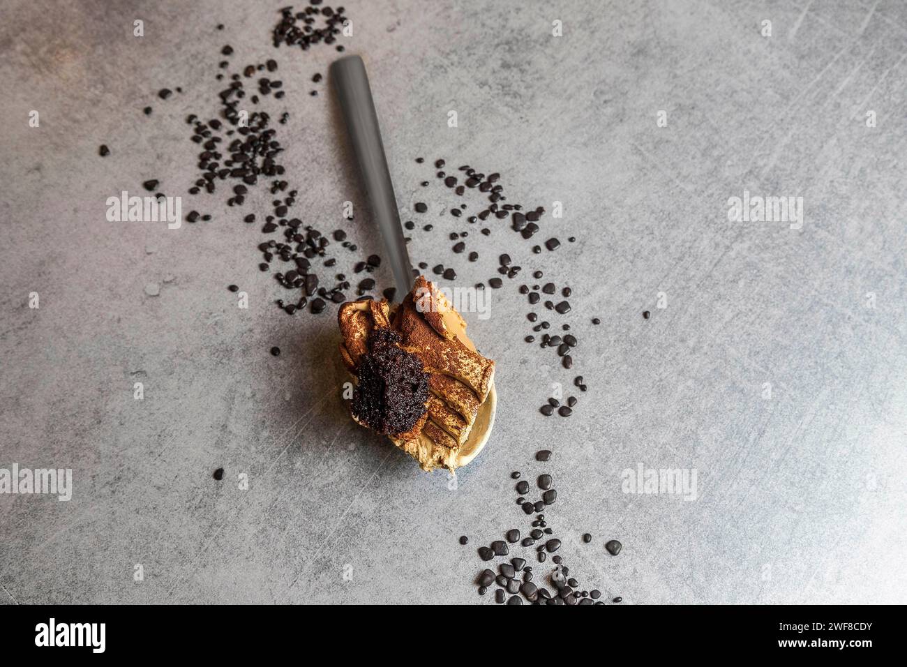 Löffel voller Tiramisu-Eiskuchen mit Streuseln herum. Weichzeichner Stockfoto