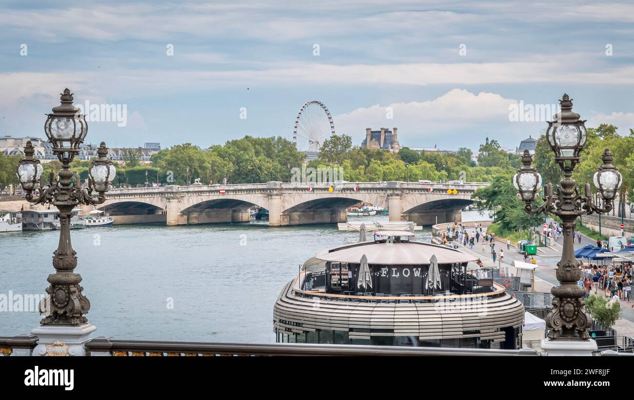Die Straßenbeleuchtung und Reflexionen auf dem Wasser mit einer Brücke, Gebäuden und einem Boot, Paris, Frankreich Stockfoto