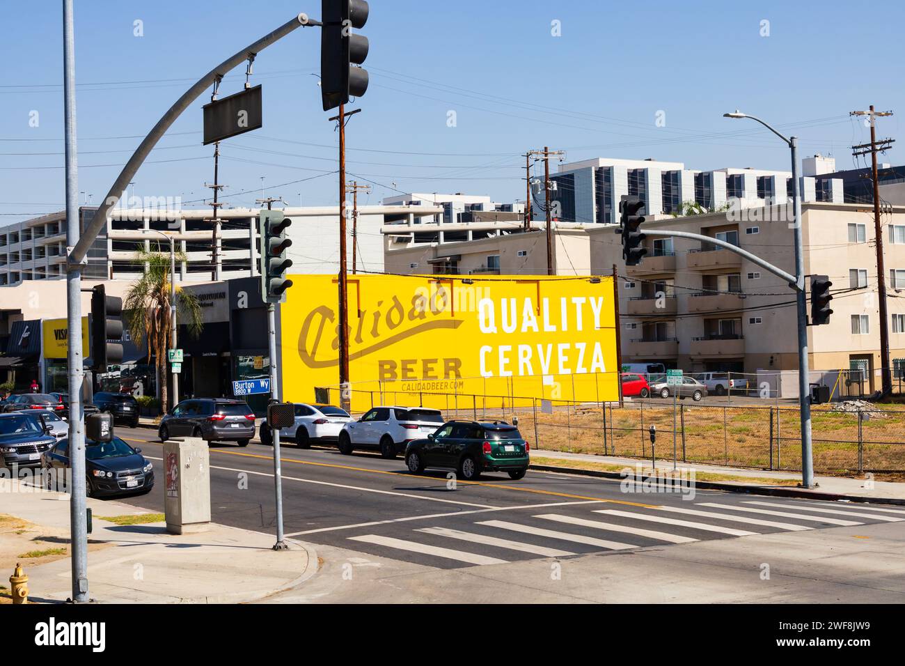 Verkehr an der Kreuzung von Robertson Boulevard und Burton Way mit großem Werbeschild für Calidad Beer Stockfoto