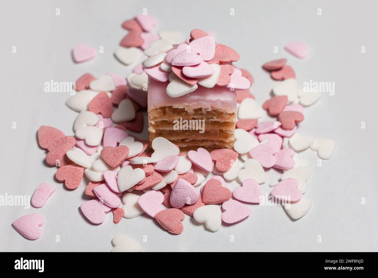 Kleiner Kuchen, bestreut mit dekorativen herzförmigen Zuckerperlen Stockfoto