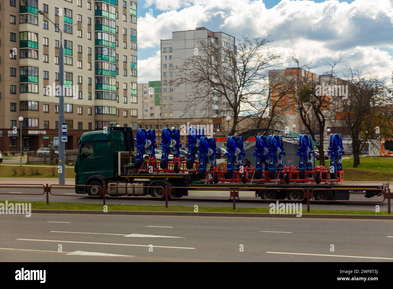 Transport großer agrokomplexer Maschinen zur Kultivierung und Aussaat von Erntegut auf langen Anhängern mit LKW entlang der Straße in der Stadt Stockfoto