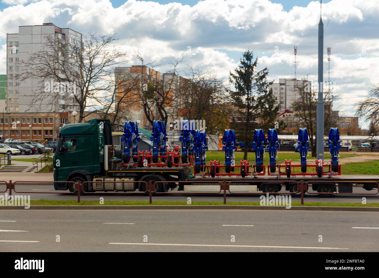 Transport großer agrokomplexer Maschinen zur Kultivierung und Aussaat von Erntegut auf langen Anhängern mit LKW entlang der Straße in der Stadt Stockfoto