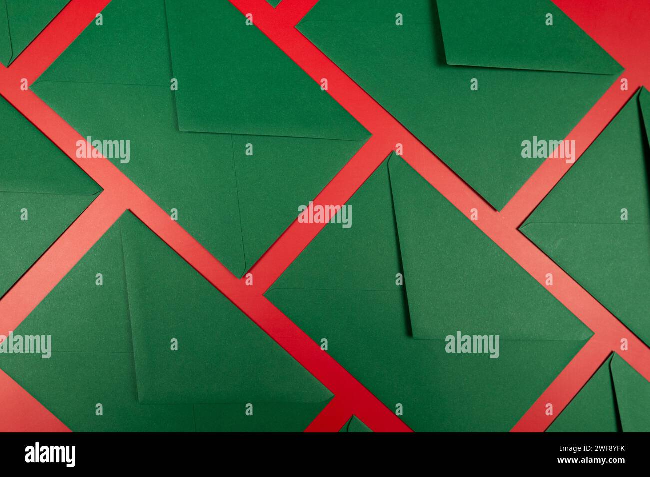 Draufsicht grüner Umschläge auf rotem Hintergrund. Weihnachten, Neujahrskomposition. Pfosten Sie Flat Lay, Kopierraum. Stockfoto