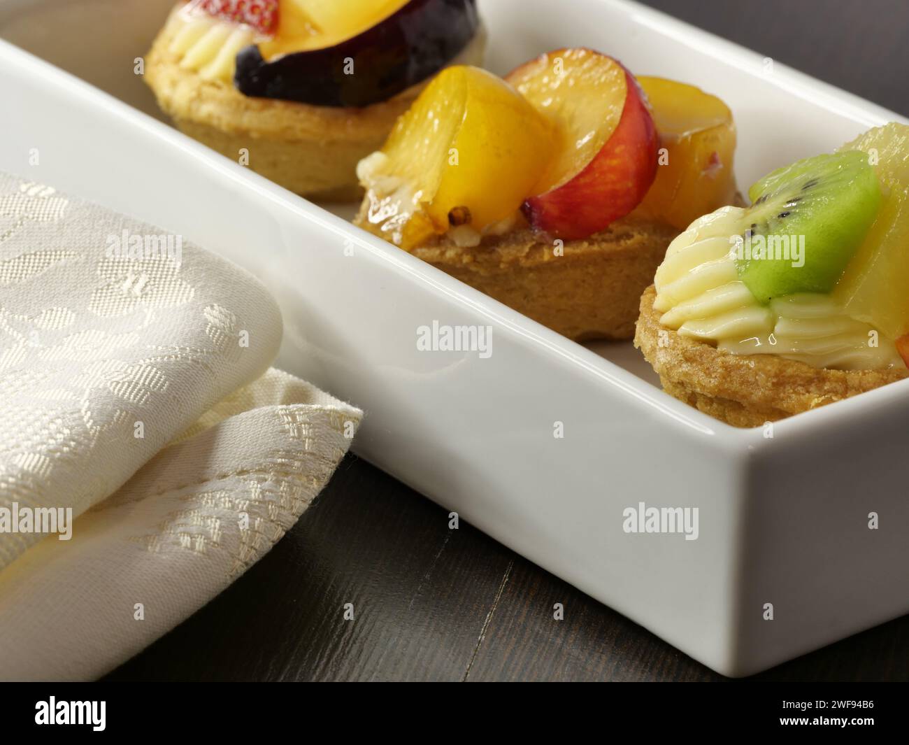 Zwei zierliche weiße Tabletts mit köstlichem Obstgebäck und frisch gebackenem Brot Stockfoto