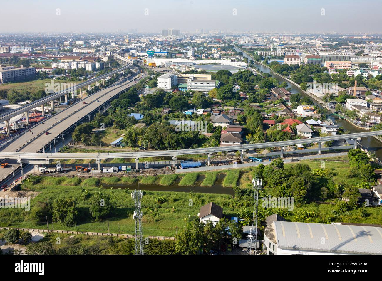 Ein Blick über den Kopf, der das Stadtbild Bangkoks unter sich mit einer belebten Autobahn, die zwischen hoch aufragenden Gebäuden und der belebten Stadtlandschaft schlängelt, erfasst. Stockfoto
