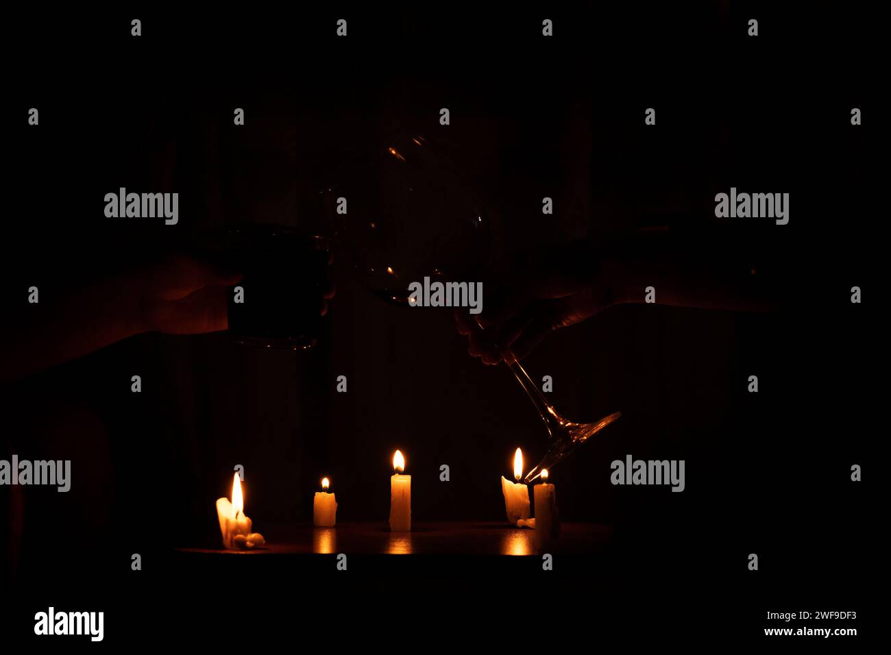 Die Hand einer Frau und eines Mannes klirren zwei Gläser Wein zu Hause bei Kerzenschein, romantische Hausfeier, Trinken, Urlaub Stockfoto