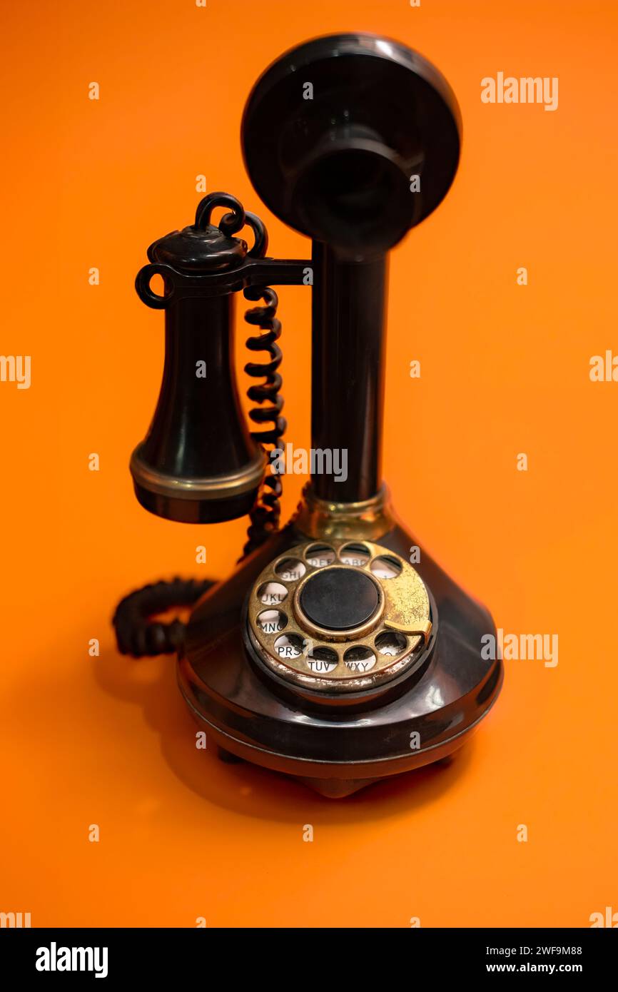 Vintage Drehwahltelefon auf einem hellen orangefarbenen Hintergrund Stockfoto